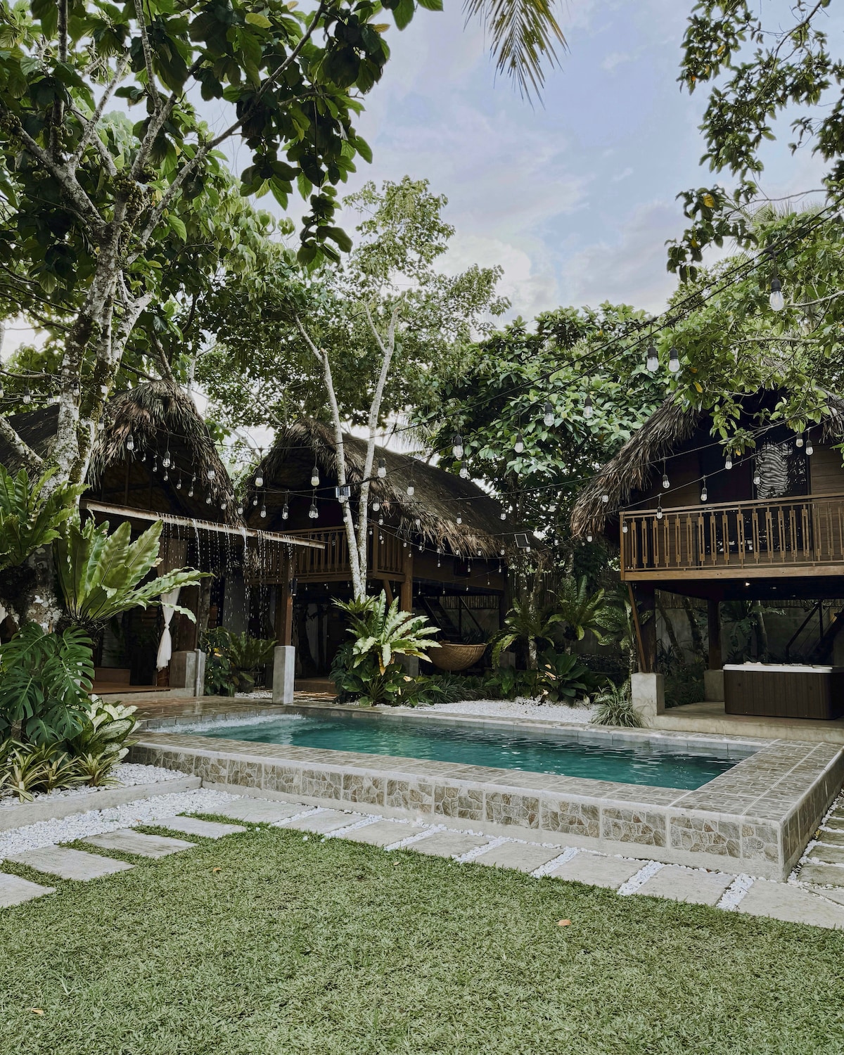 Amadeo property pool and garden with string lights at dusk
